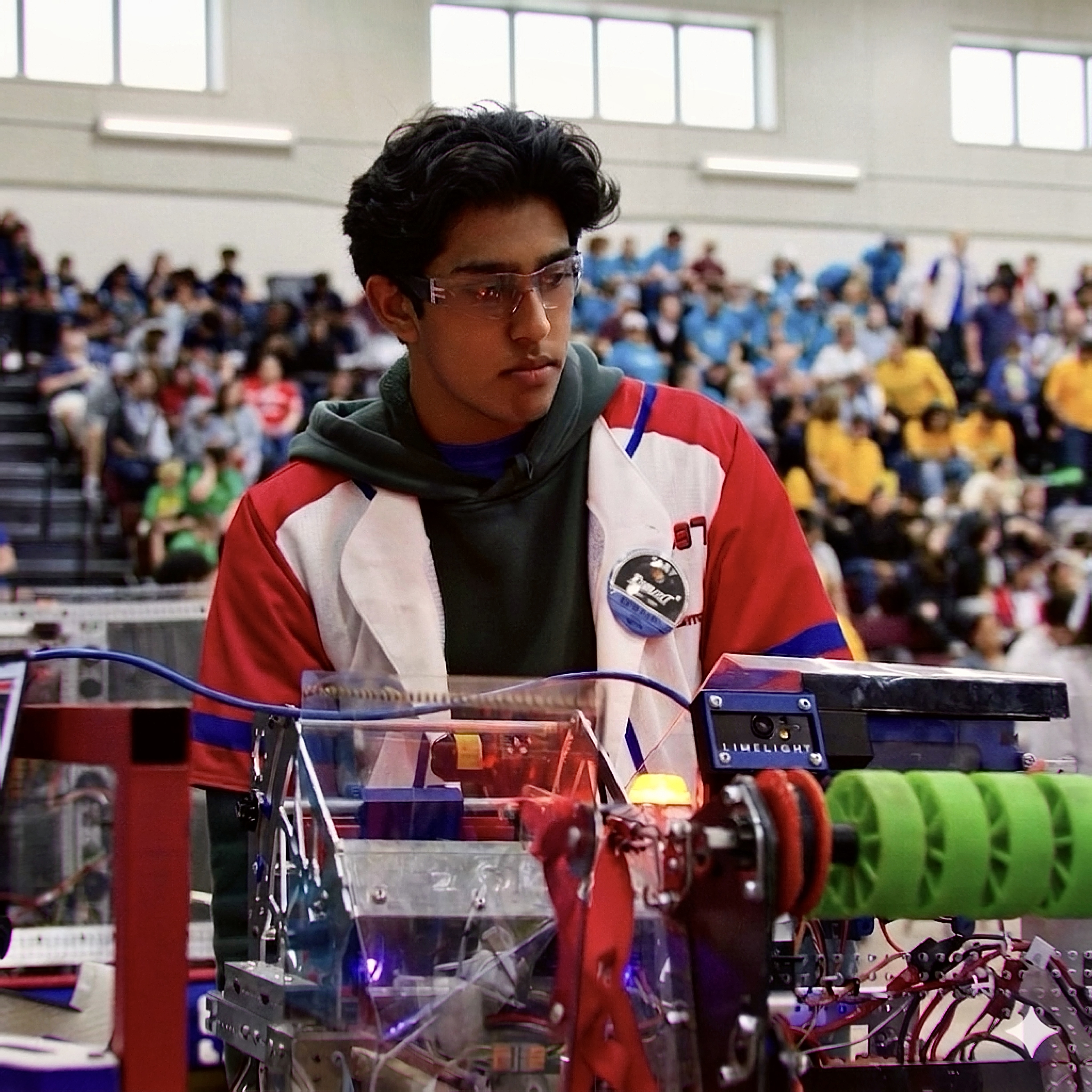 Advait Johari working beside a competition robot at a FIRST Robotics event.